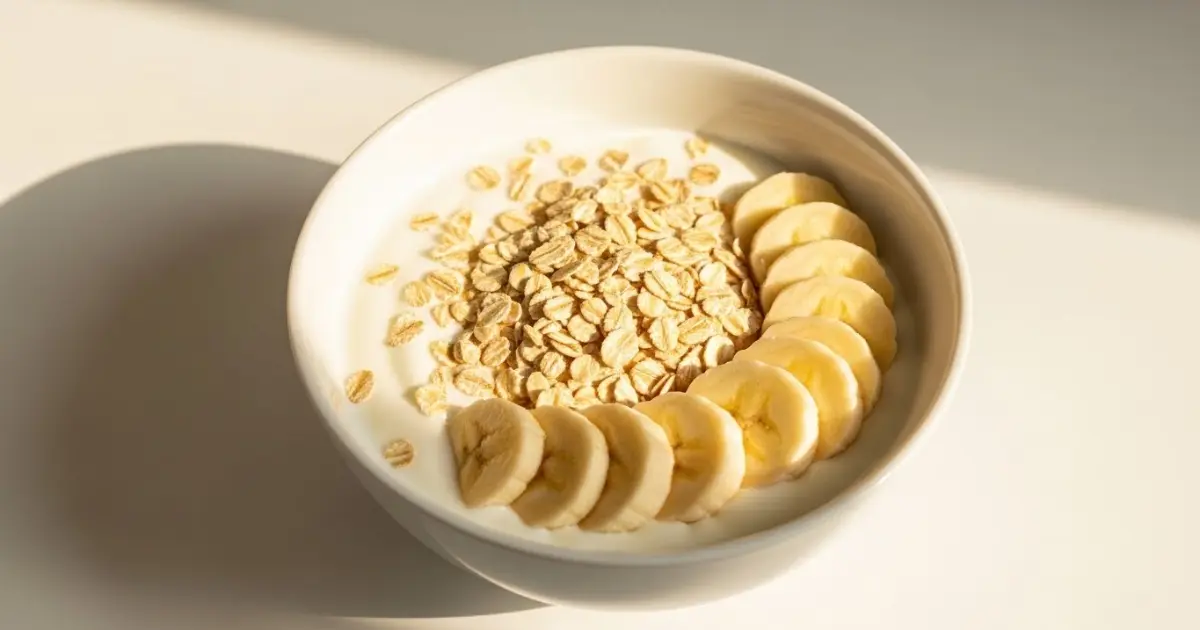Tigela de iogurte natural com aveia e banana, alimentos probióticos e prebióticos para a flora intestinal.